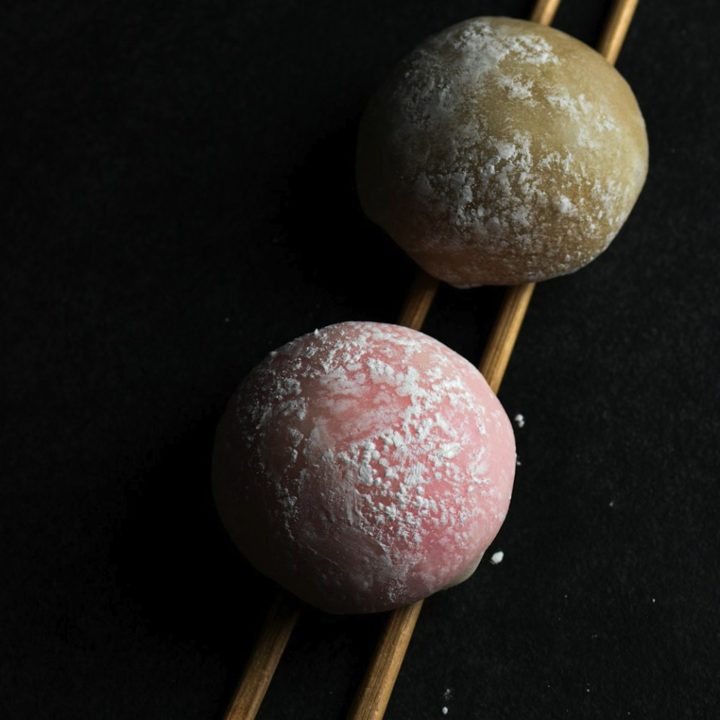 Due mochi, uno rosa e uno verde, su bacchette di legno